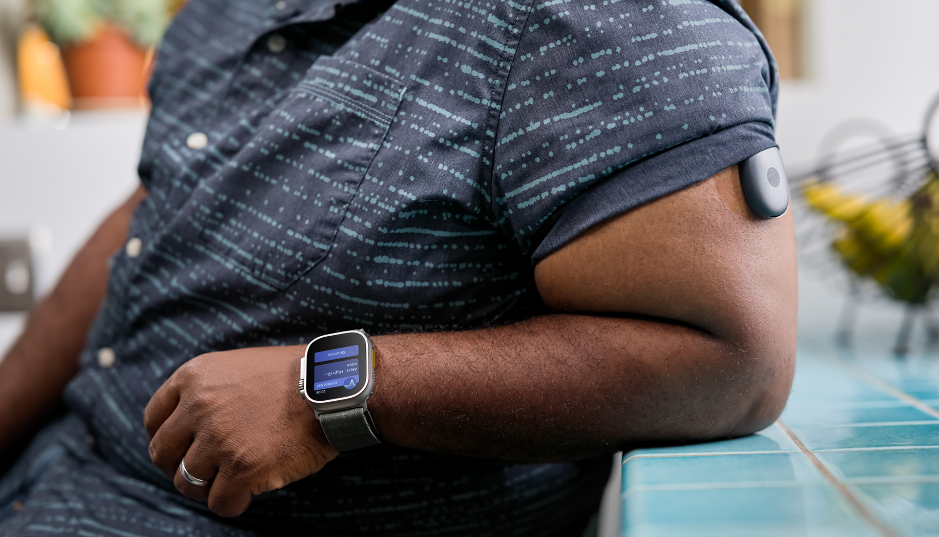An Eversense user wearing a smartwatch displaying glucose data, with a glucose monitor on their arm.