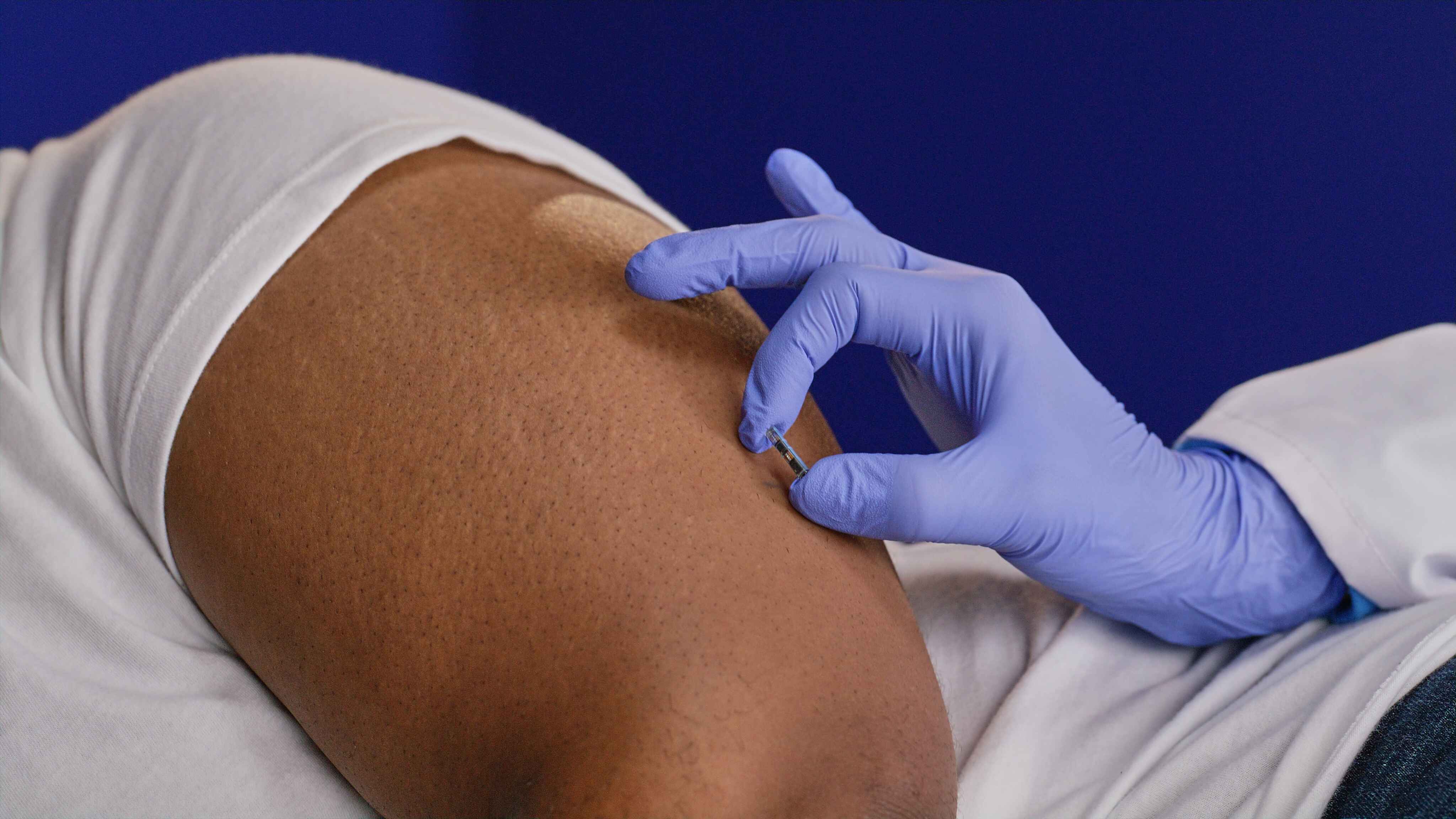 Close-up of a healthcare provider inserting the Eversense CGM sensor into the patient’s upper arm using gloved hands.